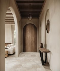 a hallway with a wooden door and white couches