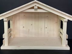 a small wooden dog house made out of wood planks and painted with white paint