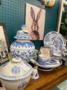 blue and white porcelain items on display in front of a framed photo with an animal print