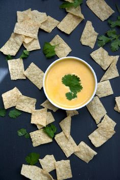 tortilla chips are scattered around a bowl of dip