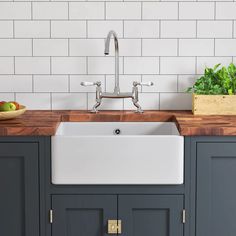 a kitchen sink sitting under a faucet next to a counter top with vegetables on it