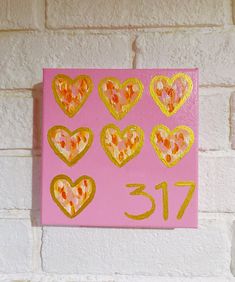 a pink wall with gold hearts on it and the number thirteen painted in yellow paint