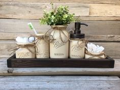 mason jars with soap and toothbrushes are sitting on a shelf next to flowers