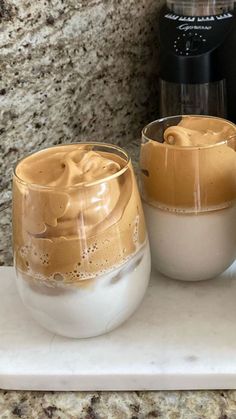 two glasses filled with liquid sitting on top of a counter