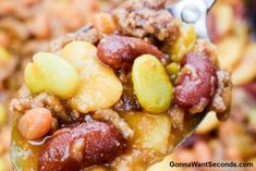 a spoon full of fruit and nuts on top of some kind of food that is ready to be eaten