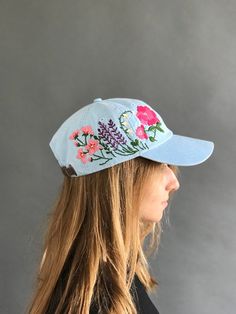 a woman with long hair wearing a blue hat that has flowers and leaves on it