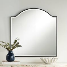 a mirror sitting on top of a table next to a vase