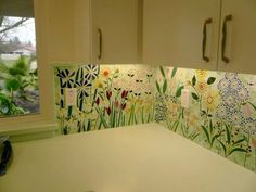 a kitchen counter with flowers painted on the backsplash and cupboards behind it