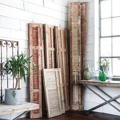 an assortment of old shutters are displayed in a room with wood floors and white walls