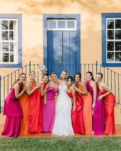 a group of women standing next to each other in front of a blue and yellow building