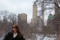 a woman is standing in the snow near some trees