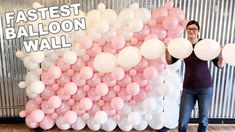 a woman standing in front of a giant balloon wall with pink and white balloons on it