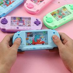 a person holding a game controller in front of four other devices on a pink surface