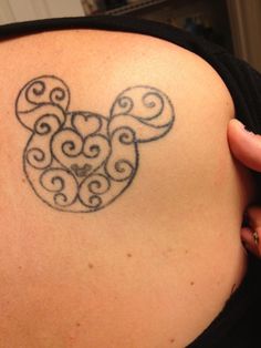 the back of a woman's shoulder with a mickey mouse tattoo design on it