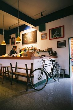 a bike parked in front of a bar with two people sitting at the counter behind it