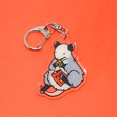 a keychain with an image of a rat holding a book on it's back