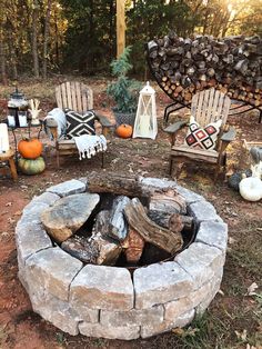 a fire pit surrounded by chairs and pumpkins on the ground with trees in the background