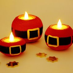 three red crocheted candles sitting next to each other on top of a table