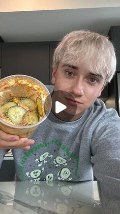 a young man holding up a bowl of food