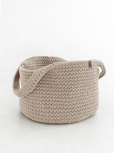 a large knitted basket with a knot on the front and bottom, sitting against a white background