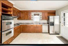 an empty kitchen with wooden cabinets and stainless steel appliances