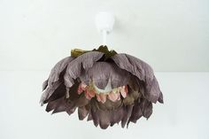 a flower is hanging from the ceiling in front of a white wall and light fixture