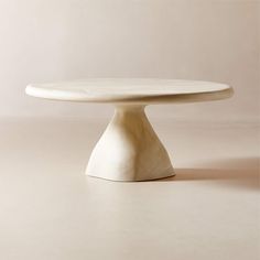 a white cake plate sitting on top of a beige tableclothed flooring area