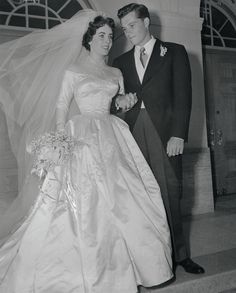 a bride and groom standing on the steps at their wedding