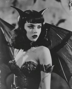 a woman dressed in devil makeup holding an umbrella