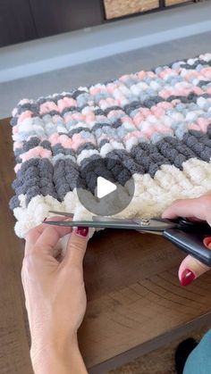 a woman is using scissors to cut the fabric on a table top with a crochet pattern