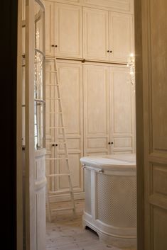 a bathroom with white cabinets and a ladder