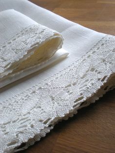 two pieces of white lace sitting on top of a wooden table