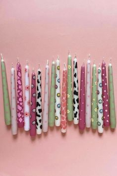 five candles with different designs on them lined up in a row against a pink background