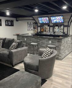 a living room filled with furniture and two tvs on top of a wall next to a bar