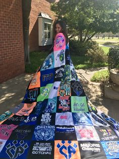 a woman standing in front of a large blanket covered in t - shirts