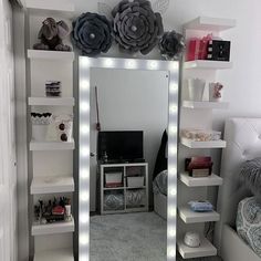 an image of a bedroom with lights on the wall and shelves in front of it