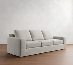 a couch sitting on top of a wooden floor next to a white wall and wood floor