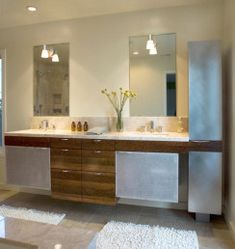 a large bathroom with two sinks, mirrors and lights on the ceiling is shown in this image