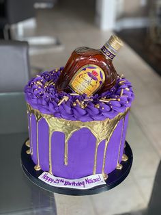 a purple cake with gold icing and a bottle of marmalade on top