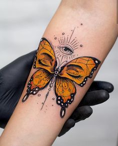 a butterfly tattoo with an eye on it's back arm and the wings are yellow