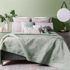 a bedroom with green walls and a bed covered in a comforter, pillows and blankets