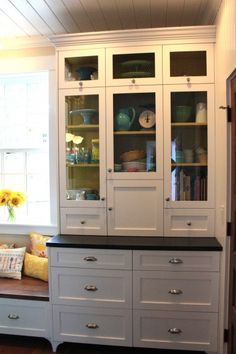 a kitchen with white cabinets and black counter tops in front of a window on the wall