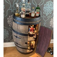 a wooden barrel filled with liquor bottles on top of a hard wood floor next to a wall