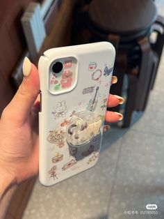 a woman holding up her phone case with pictures on it