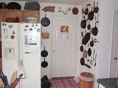 the kitchen has many pots and pans on the wall above the refrigerator, along with other cooking utensils