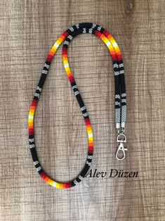 a multicolored beaded necklace on a wooden surface with the words alco dizen