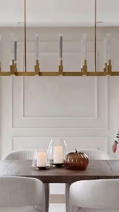 a dining room table with white chairs and candles on the end tables in front of it