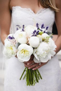 a bride holding a bouquet of white flowers