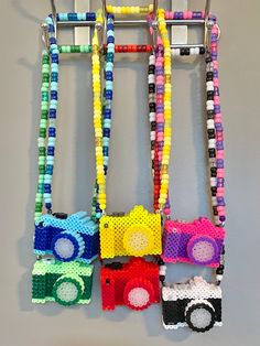 three lego cars are attached to a wall with colorful bead necklaces on them