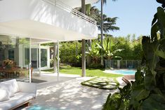 a white couch sitting on top of a patio next to a lush green forest filled with trees